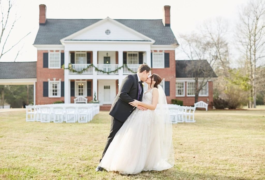 bride and groom in front of stone manor